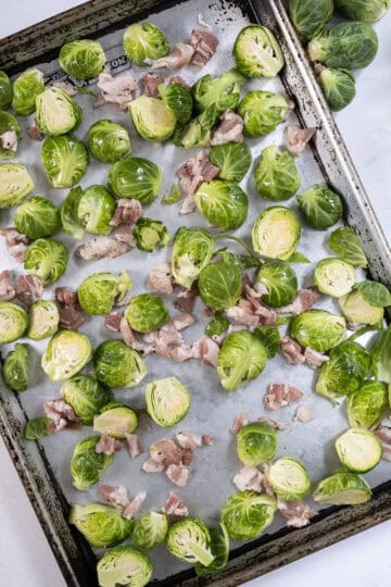 Chopped bacon and brussels sprouts on a baking tray.