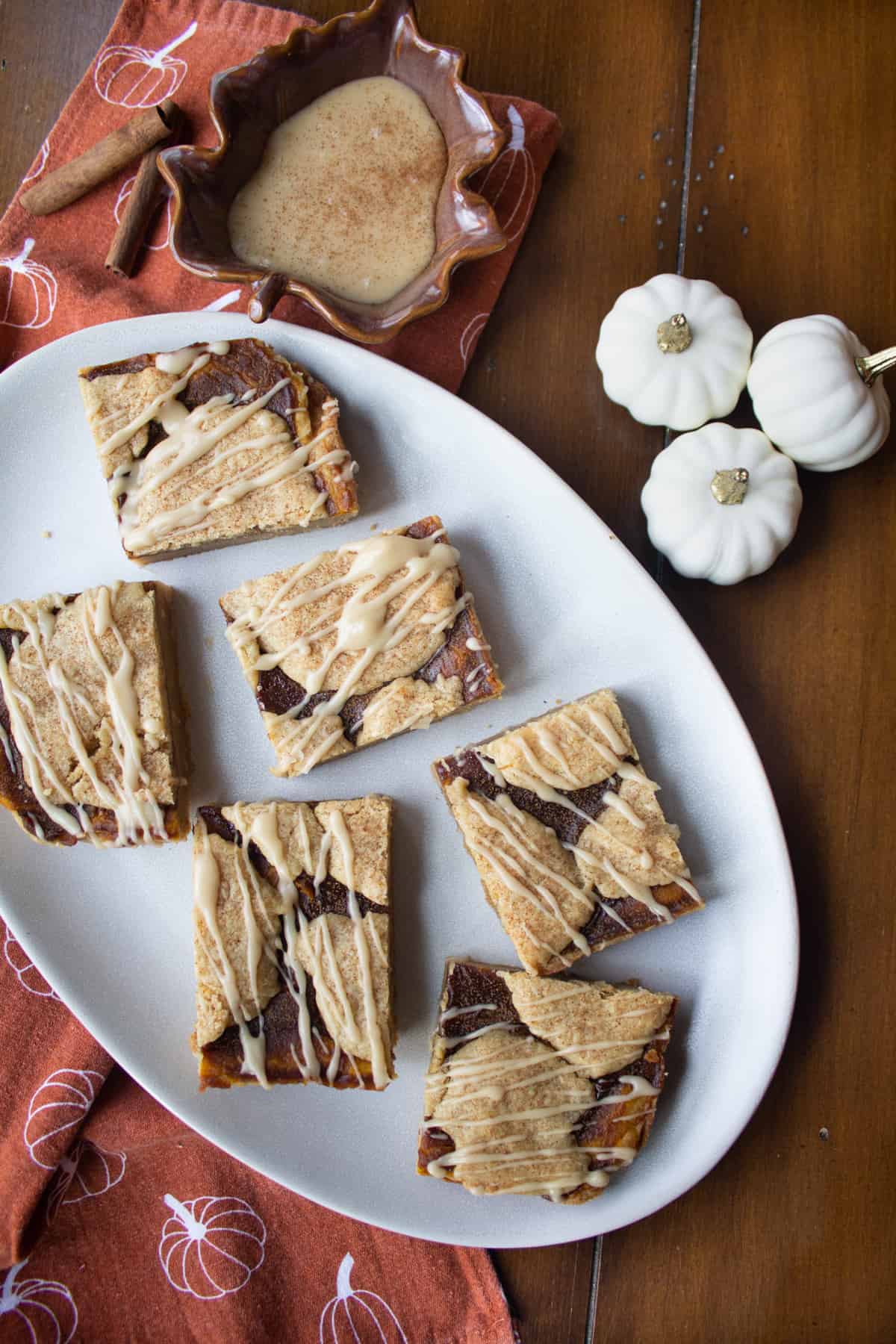 Pumpkin Butter blondies drizzled with maple glaze and side dish of maple glaze.