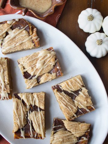 pumpkin butter blondies on a plate drizzled with maple glaze