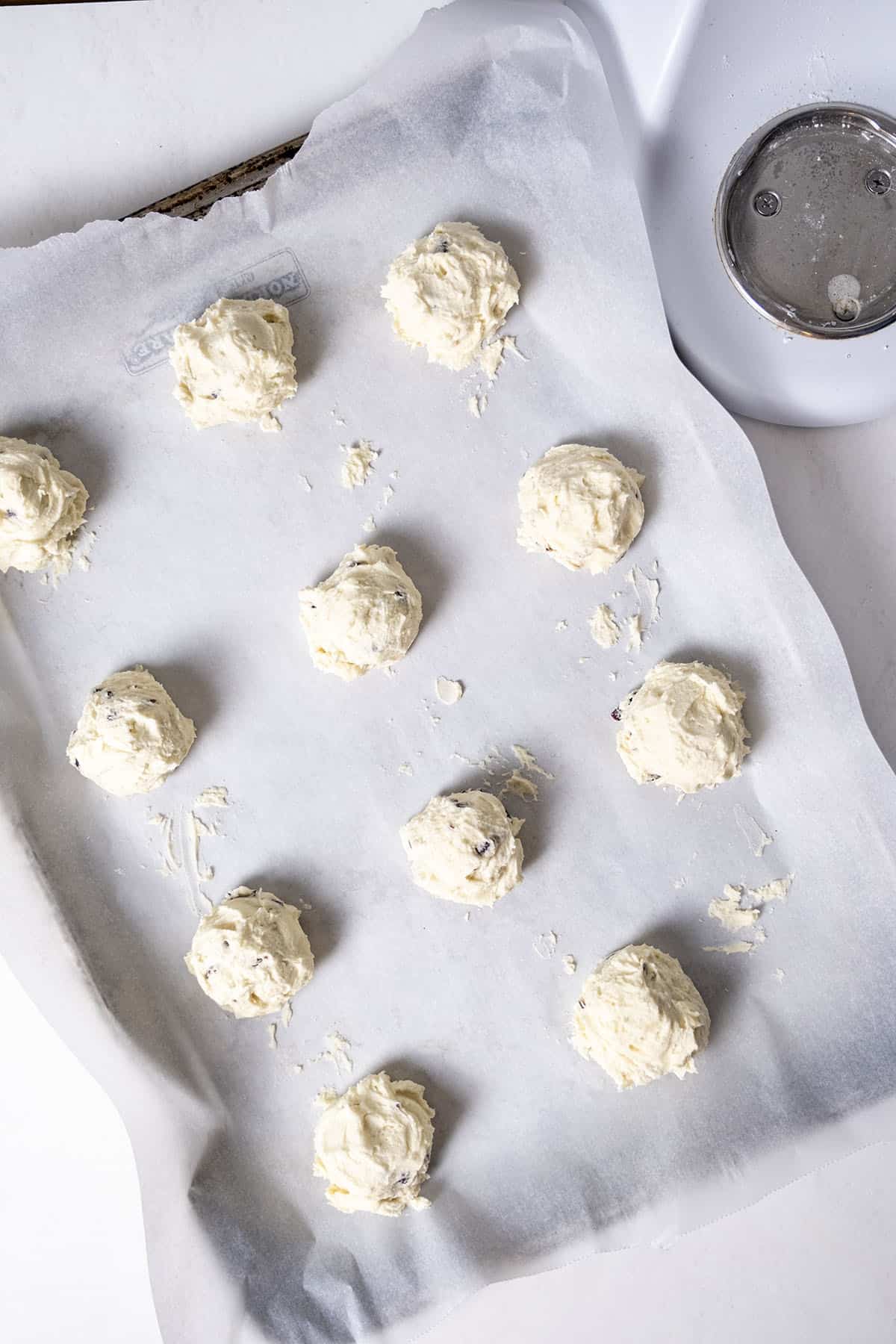 Cookie dough on a parchment paper lined baking tray.