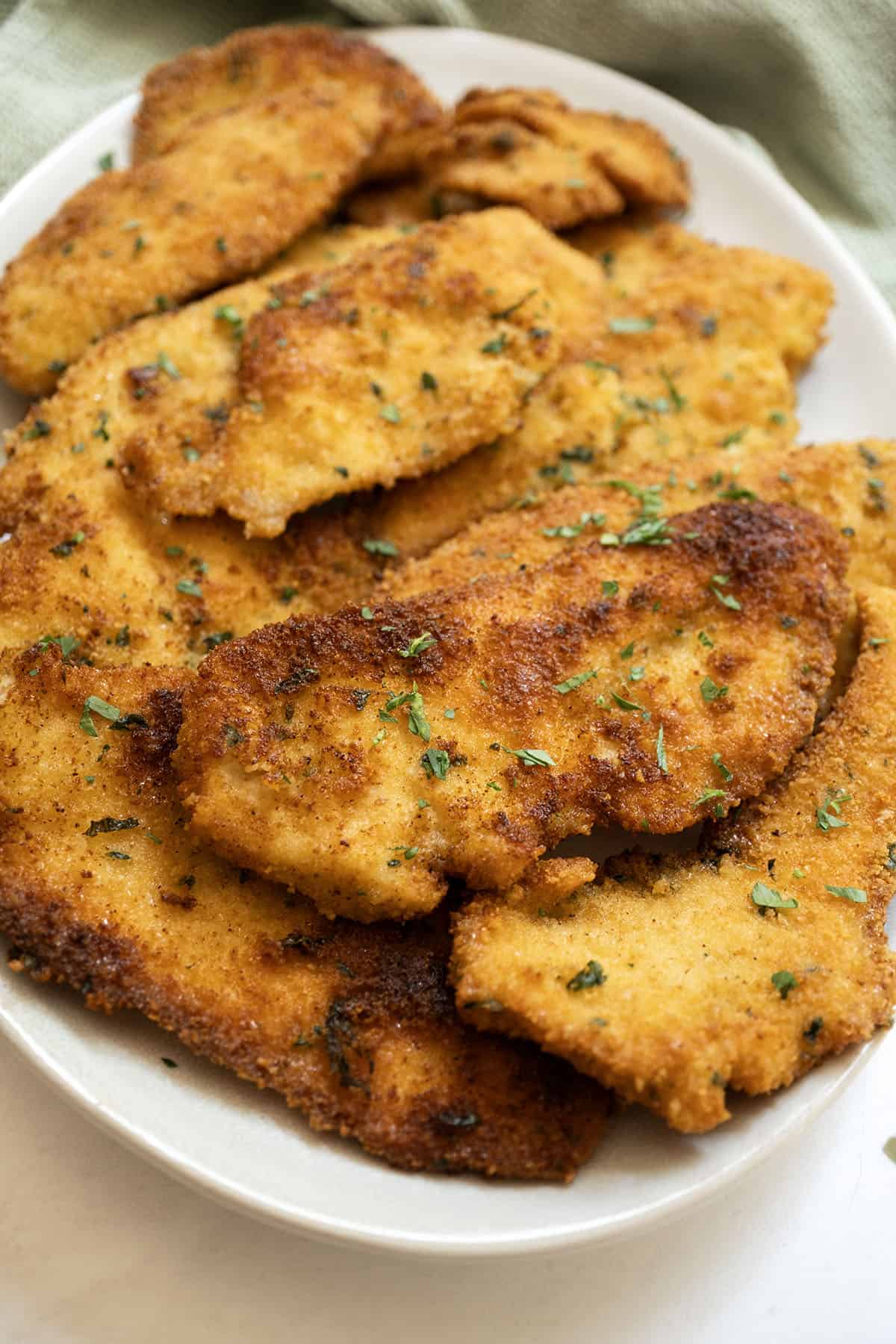 Italian chicken cutlets on piled on a plate.