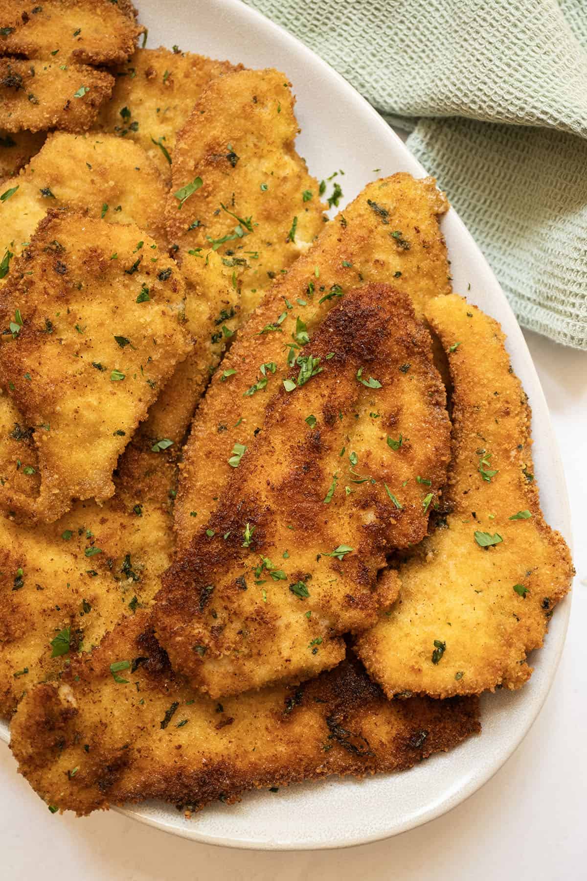 Italian chicken cutlets on piled on a plate.