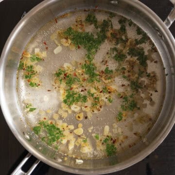 White wine and parsley in a pan coming to a simmer.