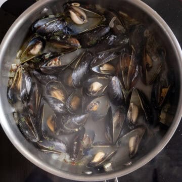 Steamed mussels opening in a pan.