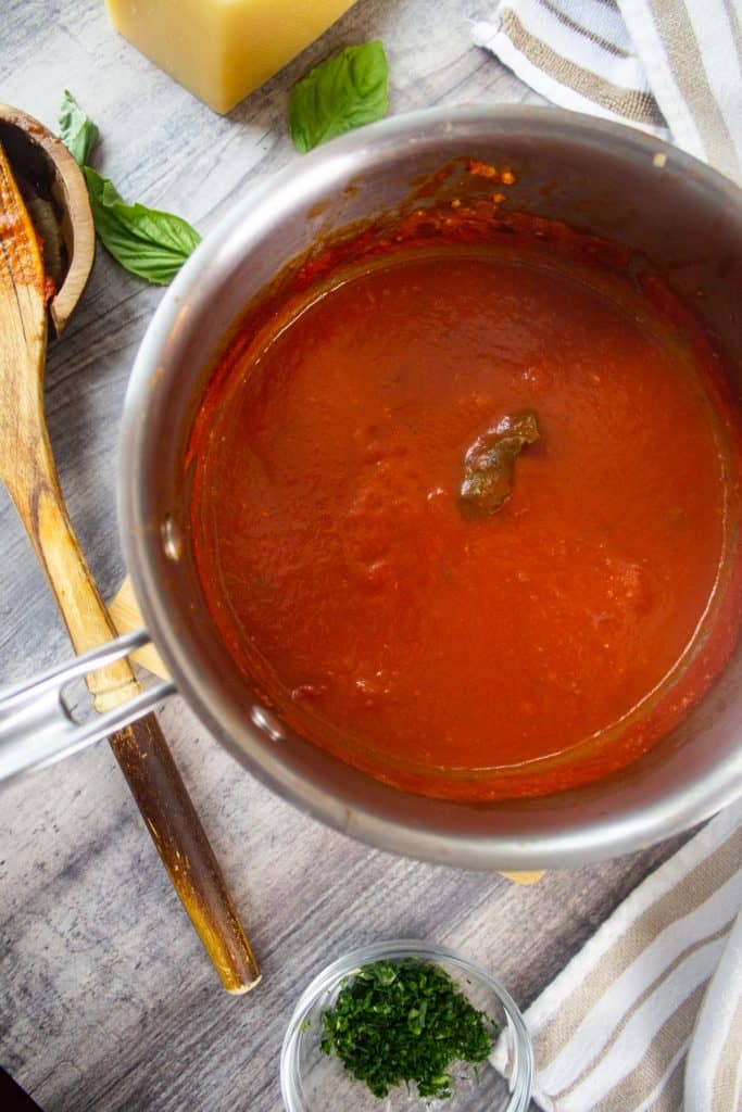 Sunday Sauce in a Pot with a wooden spoon, fresh parsley, basil and parmesan cheese