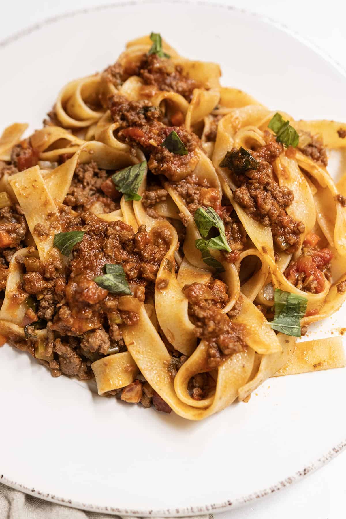 Bolognese served over pappardelle on a plate.