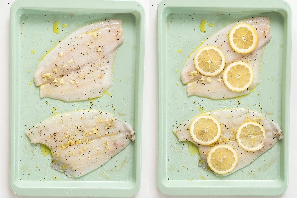 Raw flounder seasoned and topped with lemon on the baking tray.