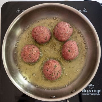 Frying raw meatballs in a saucepan.