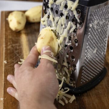 Grating potatoes on cheese grater.