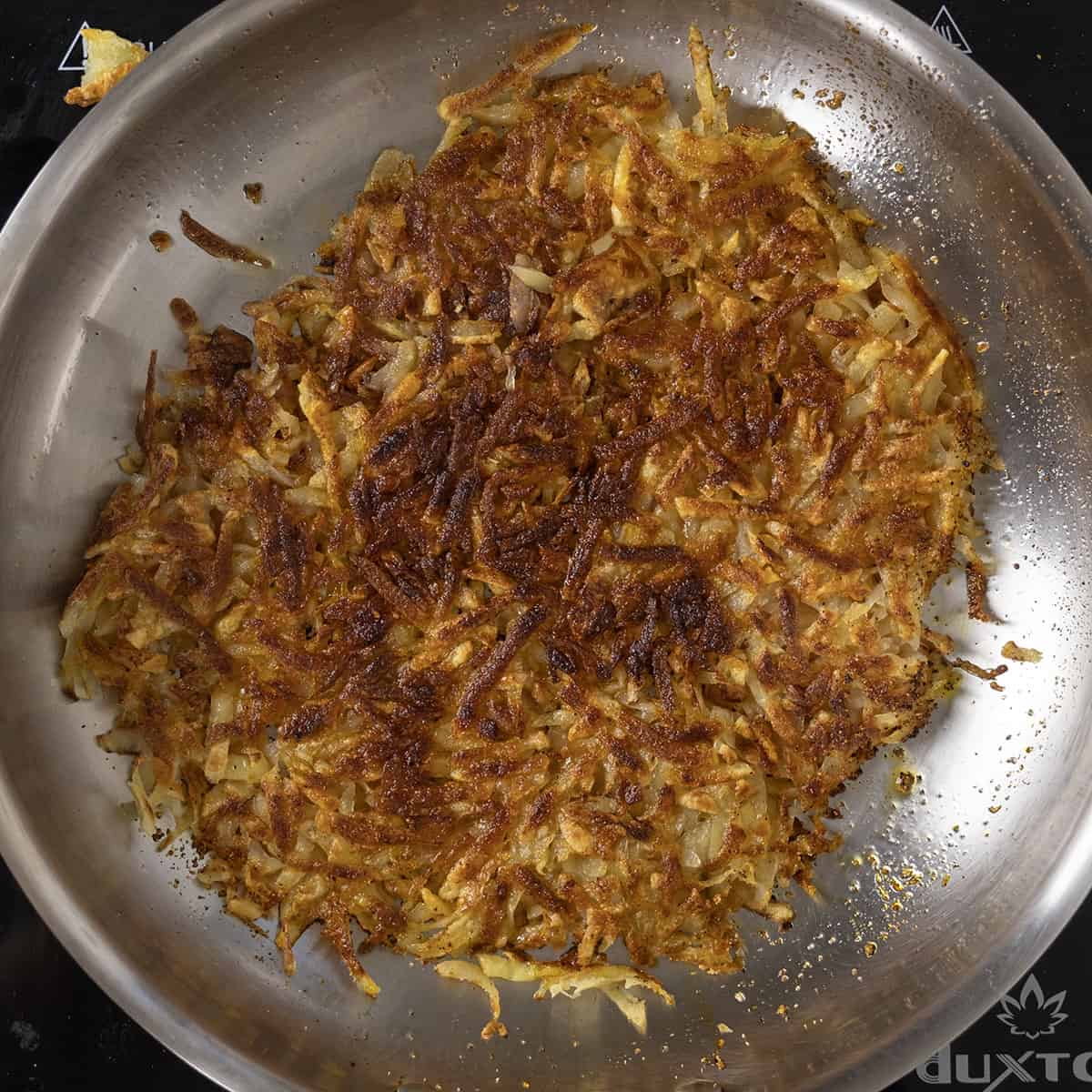 Hash browns flipped over in pan and crispy.