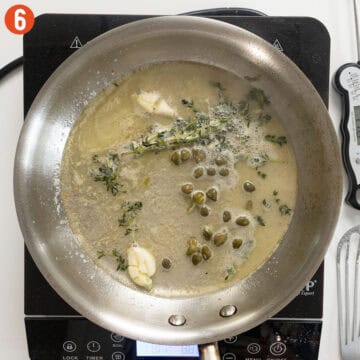 Reducing lemon, garlic, thyme sauce in a pan.