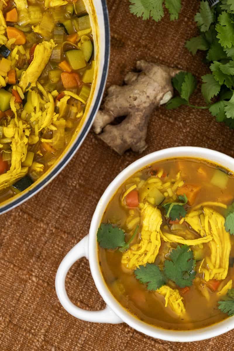 curry chicken and rice soup in a bowl and the dutch oven. side of ginger and cilantro