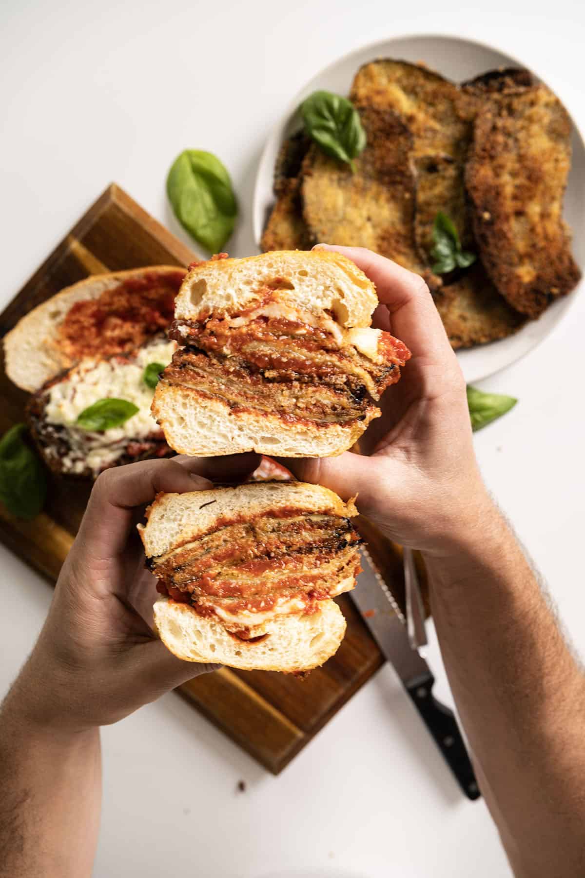 Holding an eggplant parm sandwich cut in half.