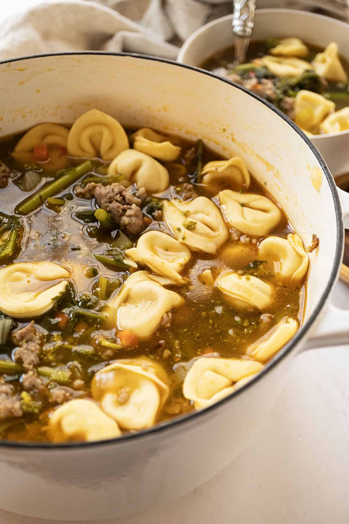 Sausage and broccoli rabe soup with tortellini in a dutch oven.