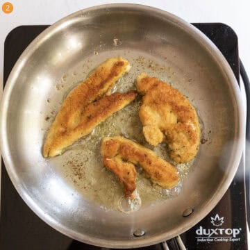 Breaded chicken tenderloins frying in the saucepan in oil.