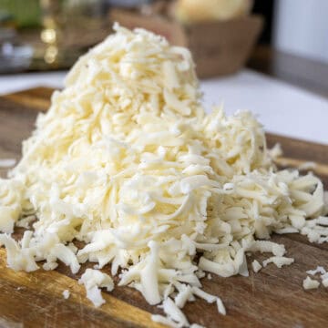 Grated baby swiss and gruyere on a cutting board.