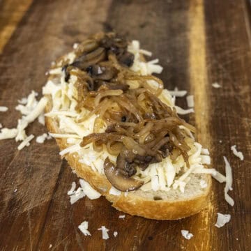 Grilled cheese being set up with cheese, mushrooms, and onions on bread.