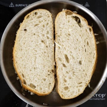 one side of grilled cheese being fried in frying pan.