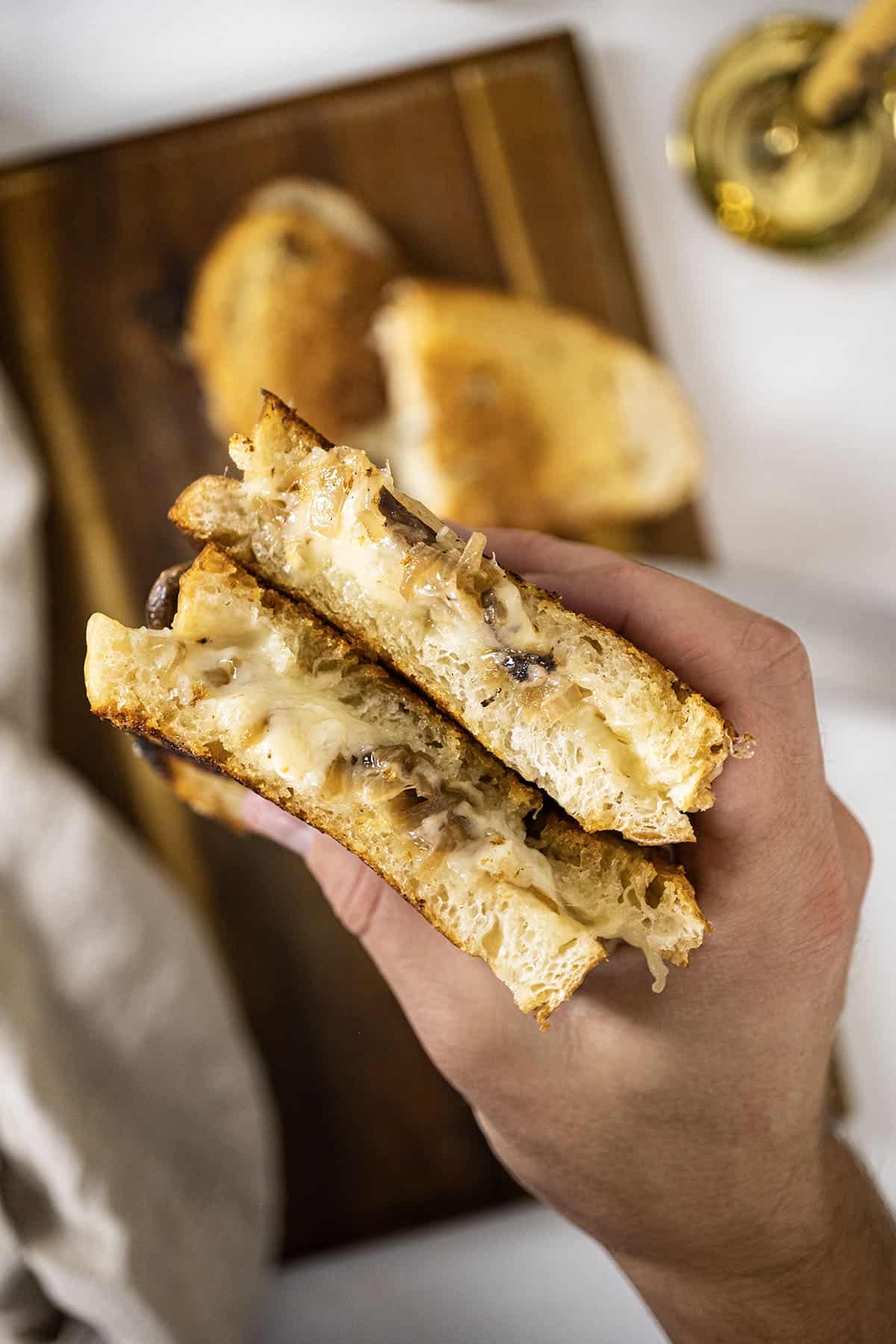 Hand holding two halves of a grilled cheese.