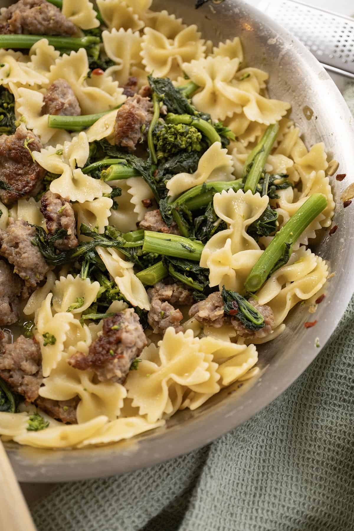 Farfalle with sausage and broccoli rabe, topped with parmesan on a plate.