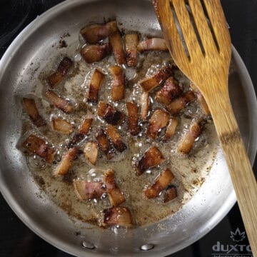 Golden brown guanciale frying in a saucepan.