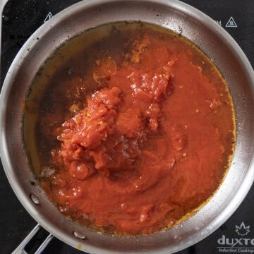 Whole plum tomatoes added to the oil from guanciale.