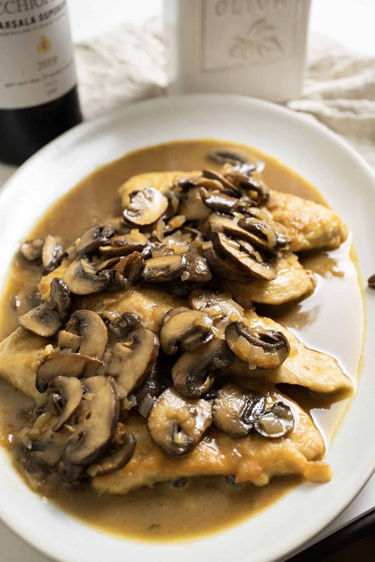 Chicken marsala with mushroom sauce served over the top of the chicken on a plate.