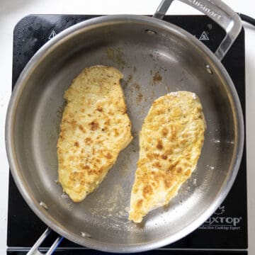 Chicken breast frying in saucepan.