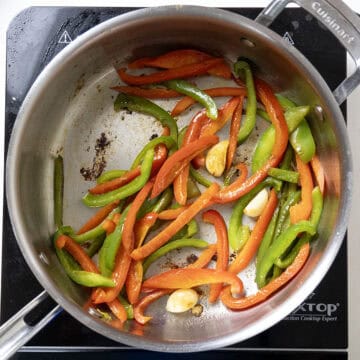 Peppers and garlic sauteing in pan.