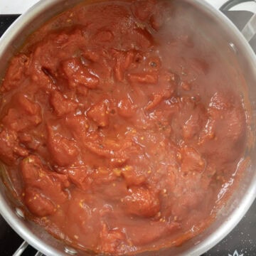 Whole plum tomatoes broken down in saucepan.