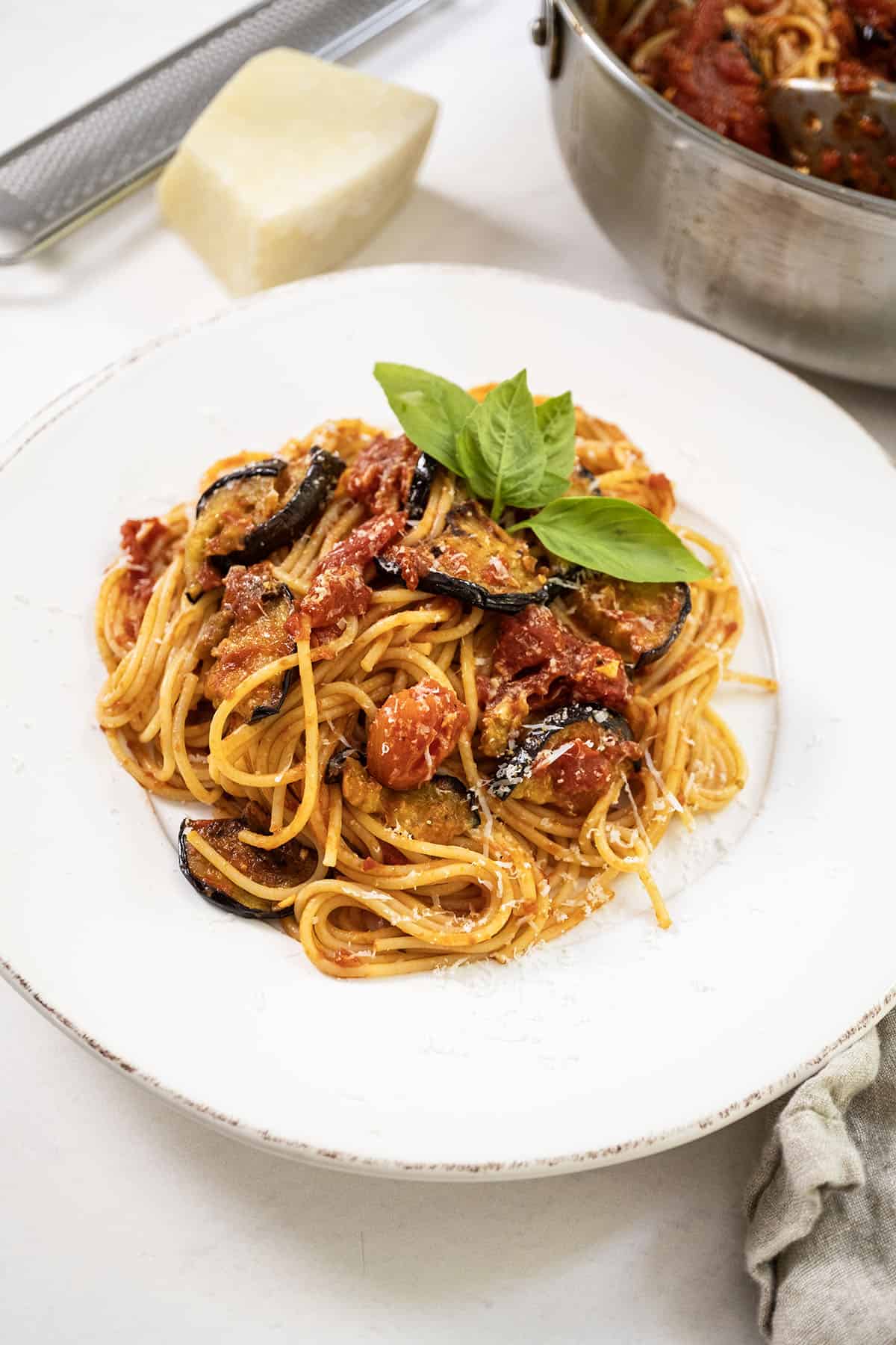 Pasta alla norma plated on a dish and garnished with basil.
