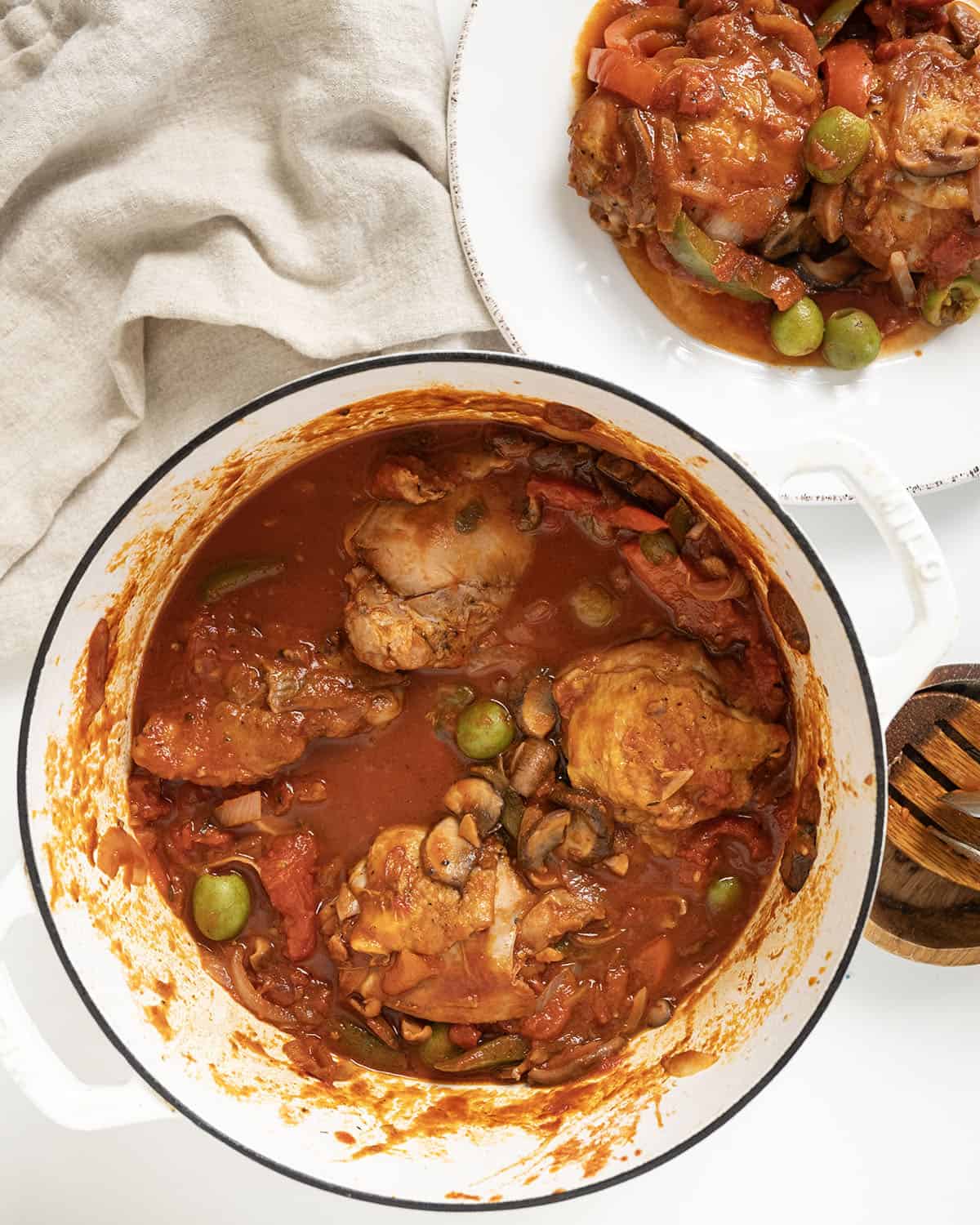 Finished chicken cacciatore on a plate and the remaining in a dutch oven.