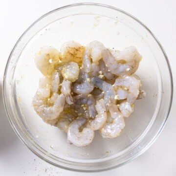 Shrimp marinating with garlic in a bowl.