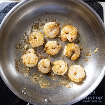 Searing shrimp in a stainless steel pan.