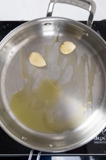 Sauteing whole crushed garlic in a pan.