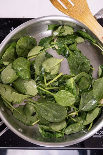 Sauteing spinach in a pan.