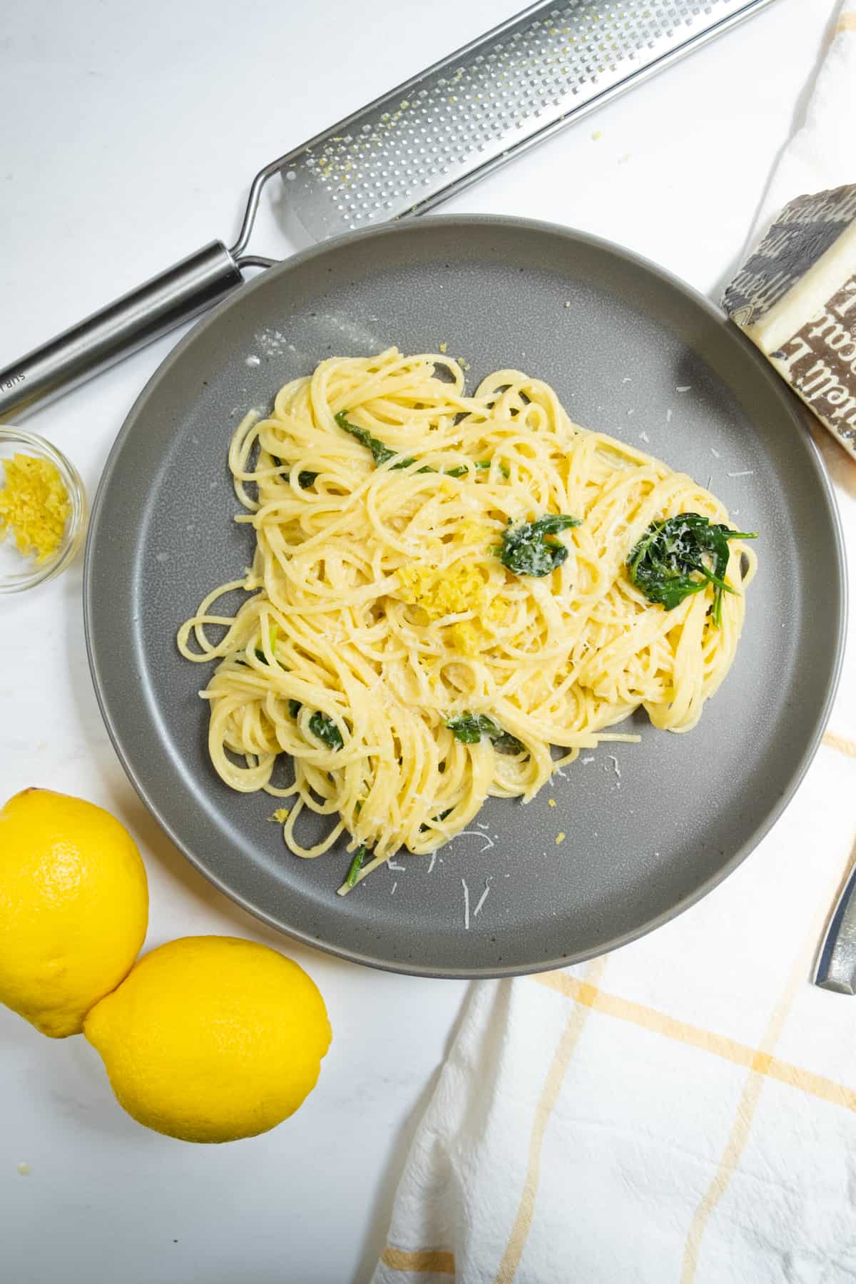Lemon spinach pasta with lemons, zest and pecorino on side.