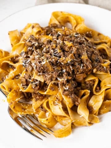 Lamb ragu over pappardelle on a small plate.