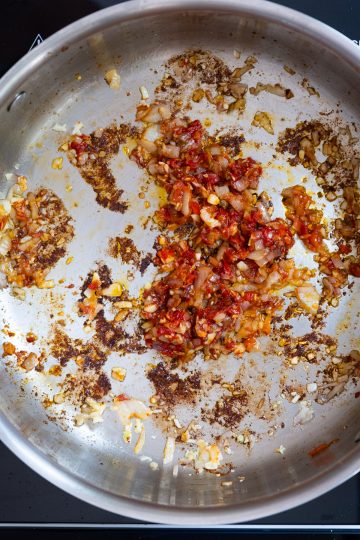 Caramelizing tomato paste and calabrian chili peppers.