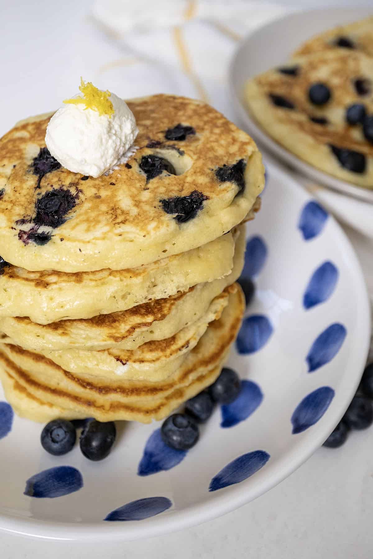Lemon ricotta blueberry pancakes on a plate with a dollop of ricotta.