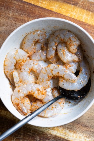 Seasoned shrimp with cayenne, garlic powder, salt and pepper in a bowl.
