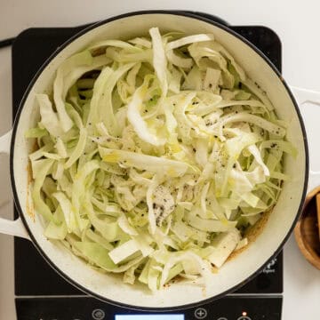 Adding cabbage to the dutch oven.