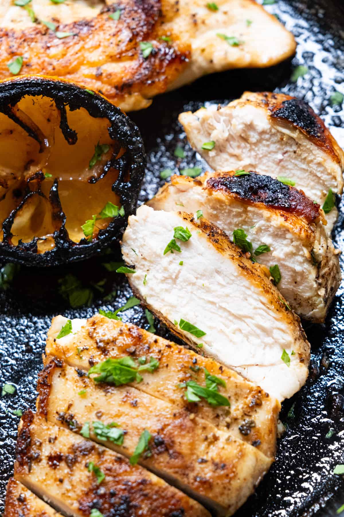 Juicy cast iron chicken breast sliced and laid on the cast iron.