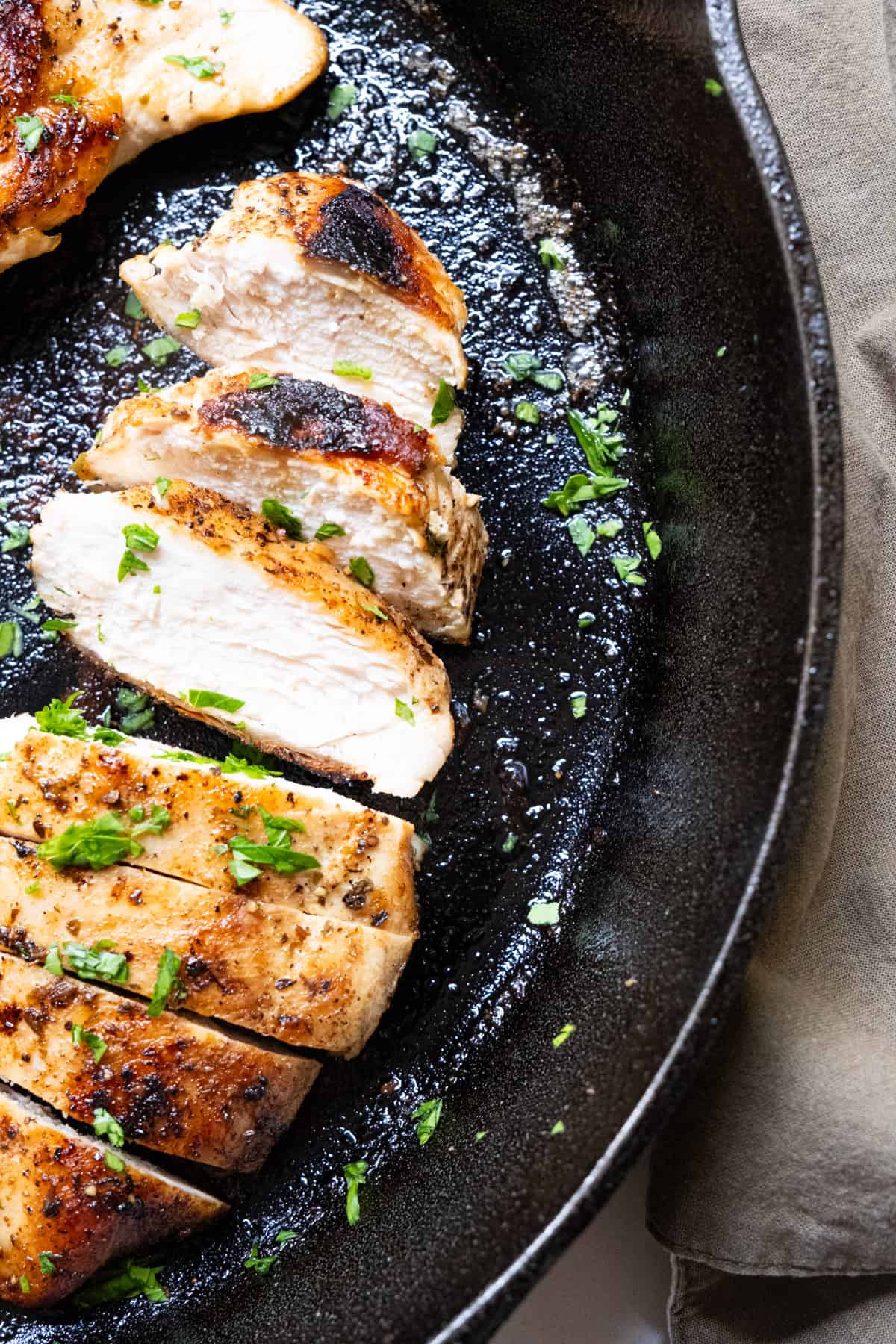Sliced chicken breast on a cast iron pan.