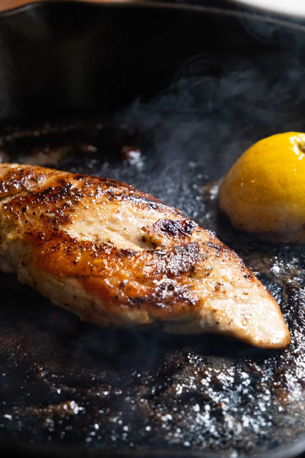 Basting the chicken breast with butter and lemon.