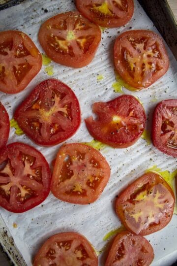 Tomatoes on sheetpan with parchment paper seasoned prior to roasting