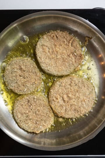 green tomatoes frying in olive oil in frying pan