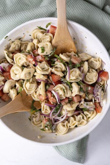 mixing ingredients into tortellini salad
