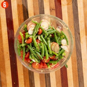 Italian green bean salad ingredients mixed together in a bowl.