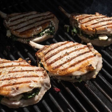 Seasoned pork chops on the grill flipped with grill marks.